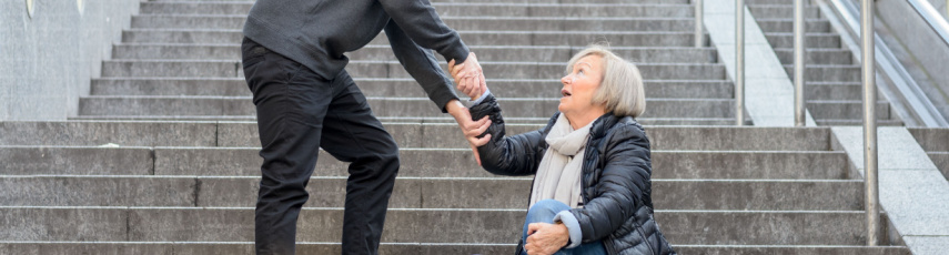 Elderly lady fallen on stairs with someone helping her get back up