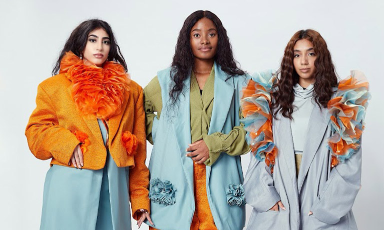 Three models wearing colourful 80's style clothing with blue, orange, green and white accents