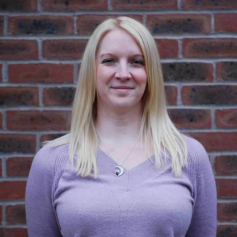 Blonde lady sitting in front of a brick wall