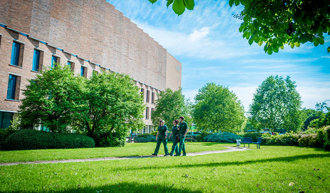 Health students walking on the grass outside the Alison Gingell building