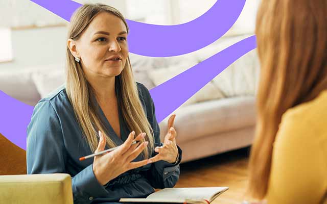 woman with long straight hair explaining something to another lady with purple swirls in the background. 