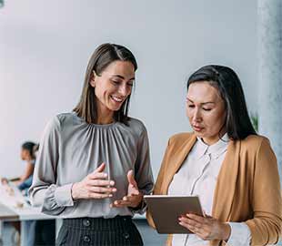 Two females in discussion one woman is holding a tablet