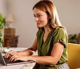 Female student with long hair working at her laptop at home