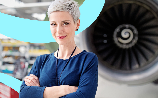 Person with short gray hair in a blue shirt and lanyard standing with arms crossed in front of an aircraft engine.