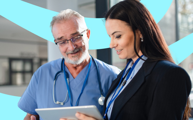 Two professionals, one in medical scrubs and the other in business attire, looking at a tablet together.