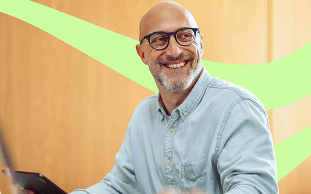 smiling bald male wearing a smart shirt with light green swirl in the background