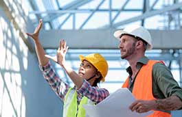 Two people wearing hard hats pointing at scaffolding