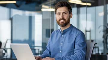 Man in a blue shirt sitting in front of a laptop