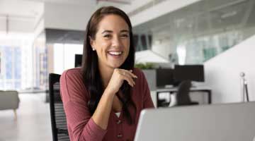 Smiling young woman sitting in front of a laptop