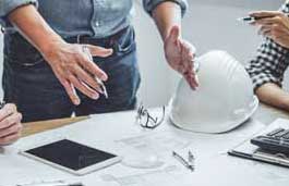 workers looking at a tablet and construction plans on a table 