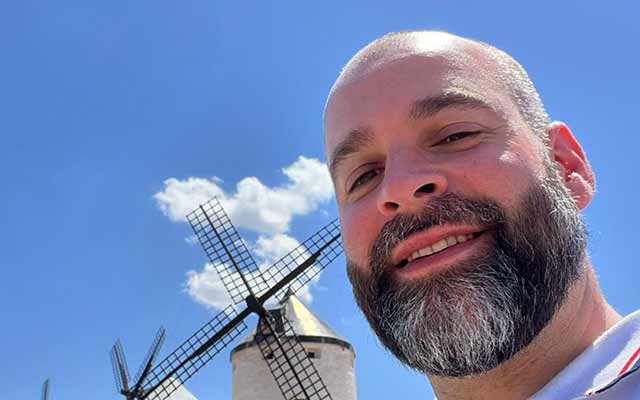 close up of Michael's face with blue sky and windmill in the background 