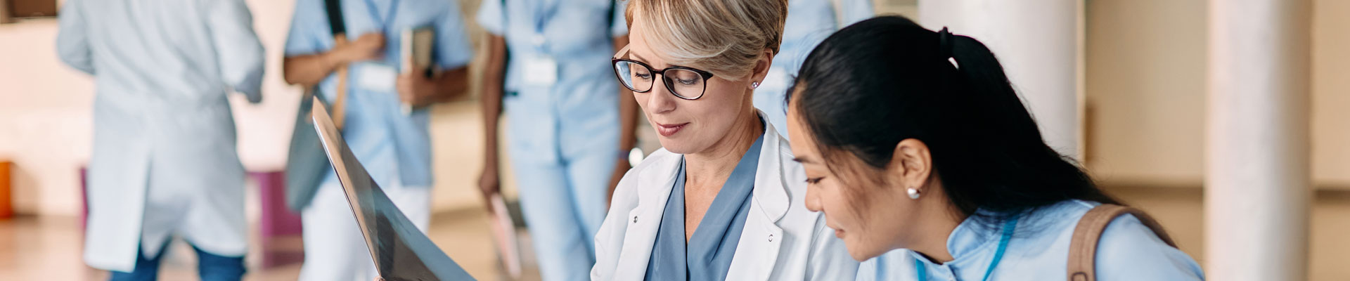 two student nurses looking at paperwork, with other students in the background