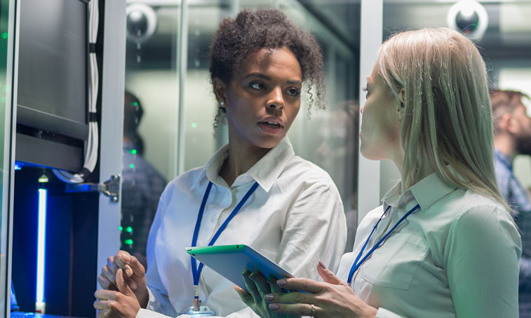 Two women working in a data centre with rows of server racks.