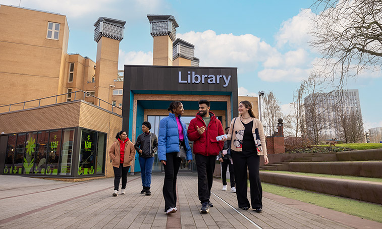 Three students stood infront of the library talking