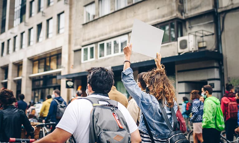 People protesting with signs on the city streets.