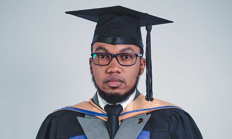 Alan Peters wearing his graduation gown and cap