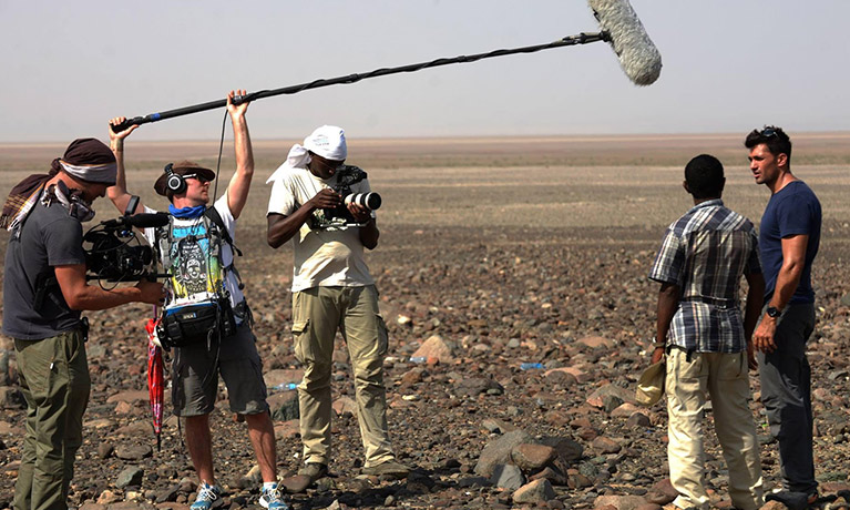 Man holding a boom mic above a presenter