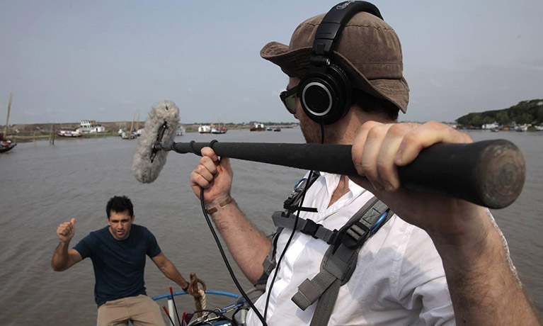 Man holding a boom mic above a presenter