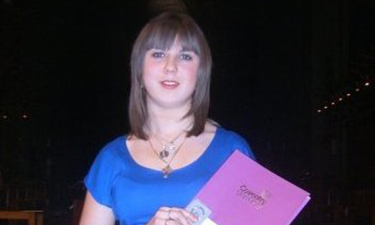 Emilei smiling holding her scholarship paper