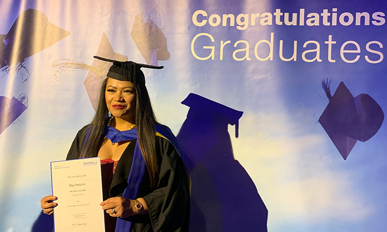 May Parsons smiling in a graduation gown and cap