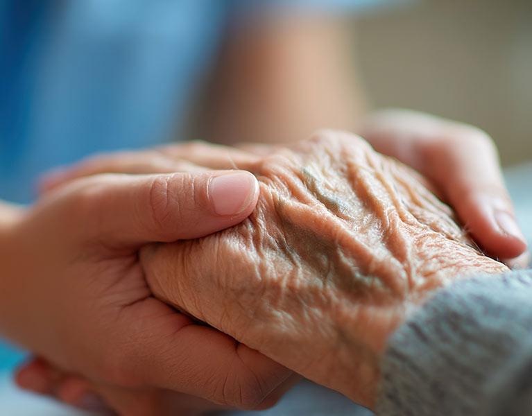 A nurse holding an elderly persons hand