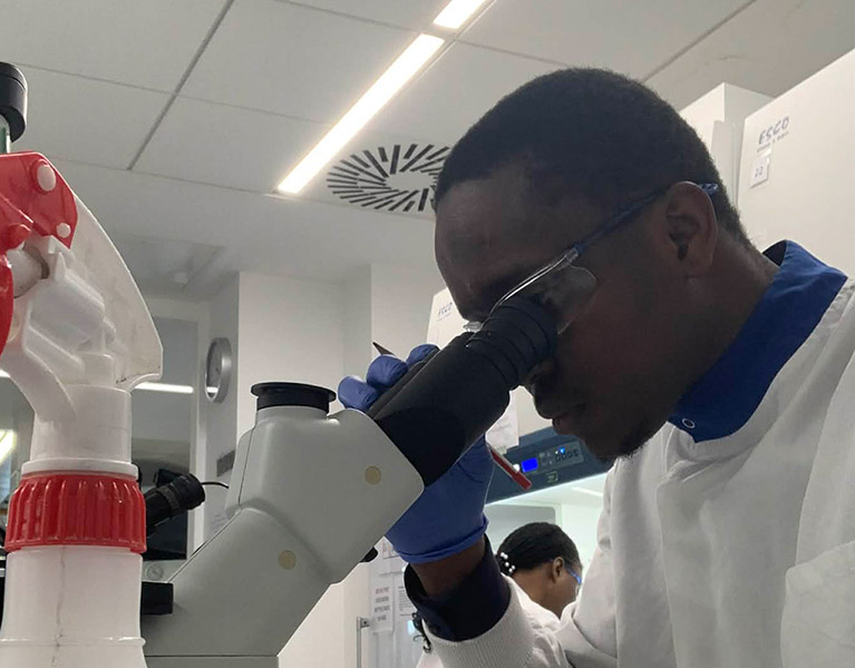 Miracle Anyabuaku looking into a microscope