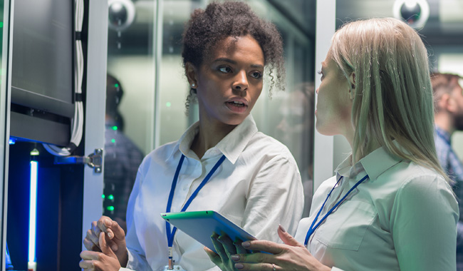 Two women working in a data centre with rows of server racks.