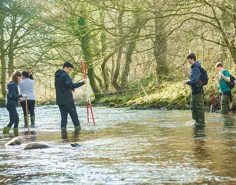 Group of students stood in shallow water measuring the flow