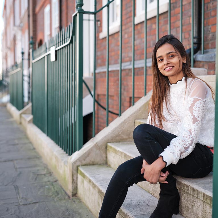 Adlin sitting on the steps of her accommodation