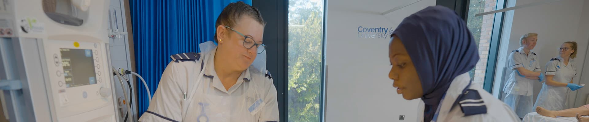 Two midwifery students holding a mannequin baby in a towel