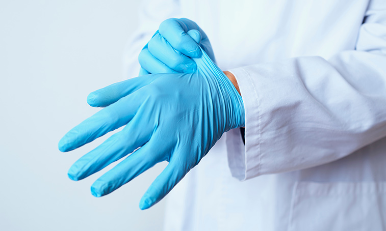 A medical professional putting PPE blue gloves on