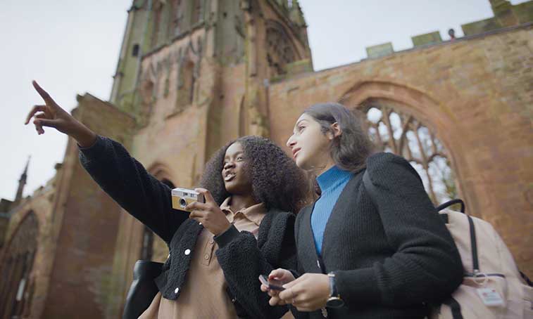 Two female students stood in the cathedral ruins