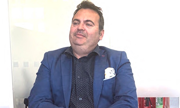 James Scozzi in a suit jacket smiling