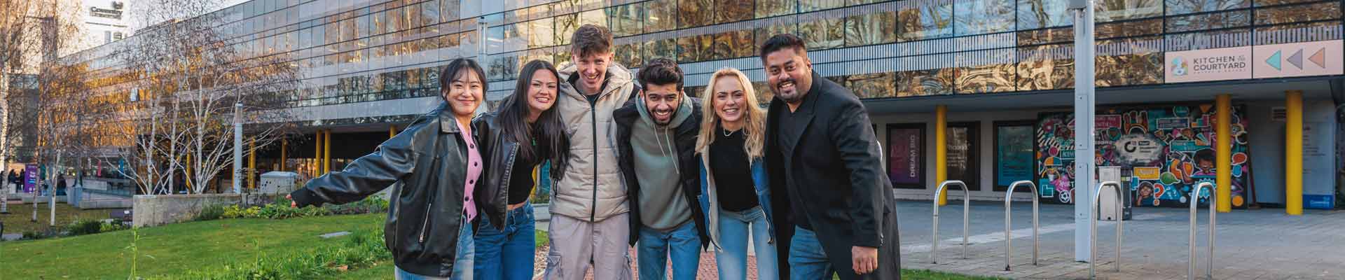 A group of students smiling together outside of Coventry university