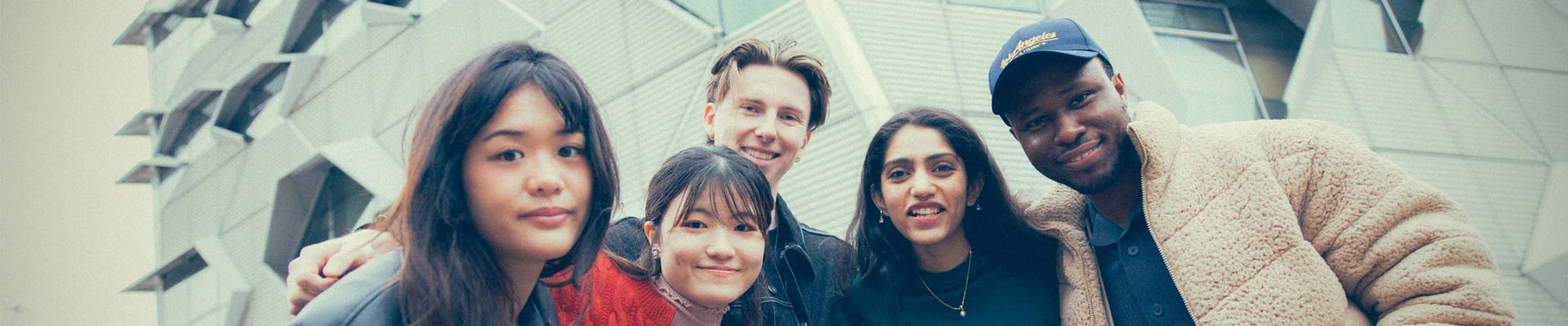 A group of students smiling infront of a building at coventry university