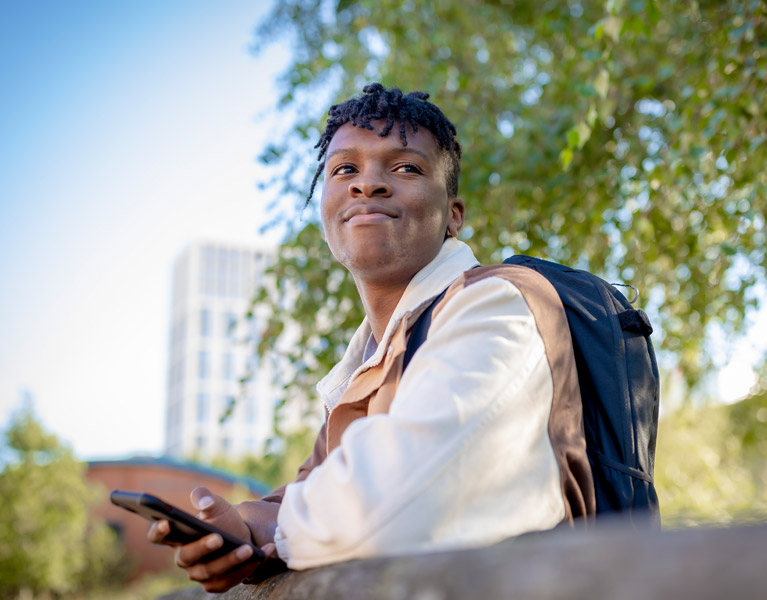 Student sat outside on a sunny day smiling