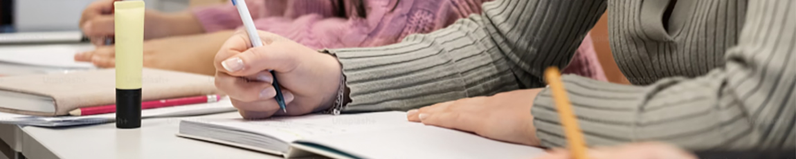 Close up of students writing in notebooks.