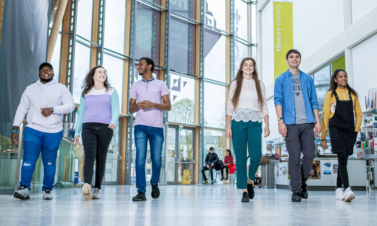 A group of multiethnic students walking through an art gallery in Coventry.