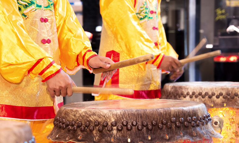 Chinese lion dance drummers in yellow silk robes beating drums.
