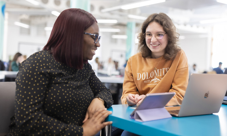 Two international students chatting in the library.