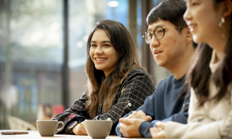 Three international students sat at a table in The Hub cafe.