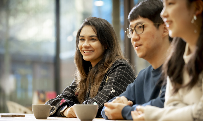 Three international students sat at a table in The Hub cafe.