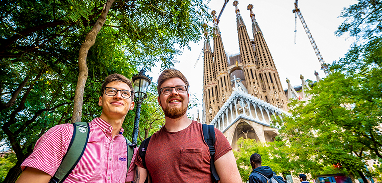 Two students on a field trip on a cloudy day standing outside of a landmark