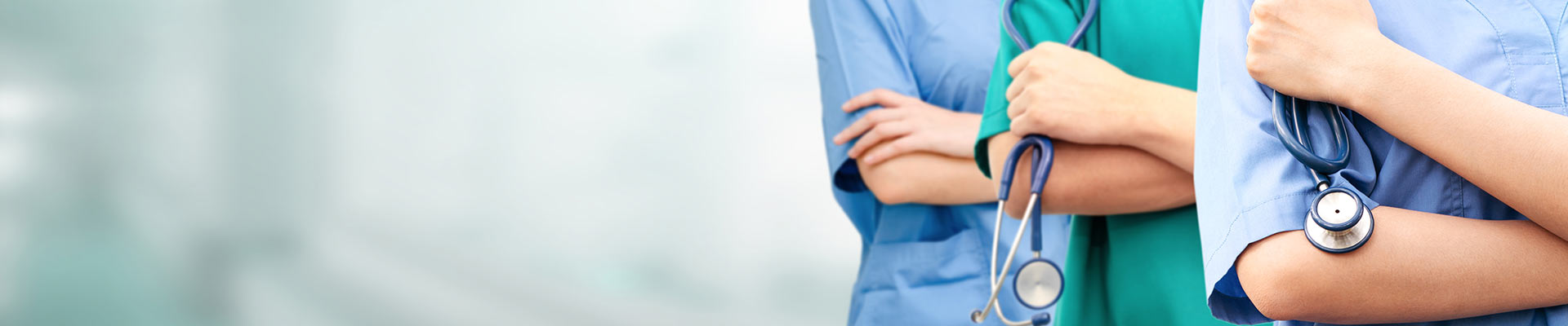 Someone writing in a notebook at a desk next to a laptop