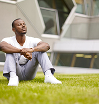 A student sitting on the grass outside the Engineering, Environment and Computing building