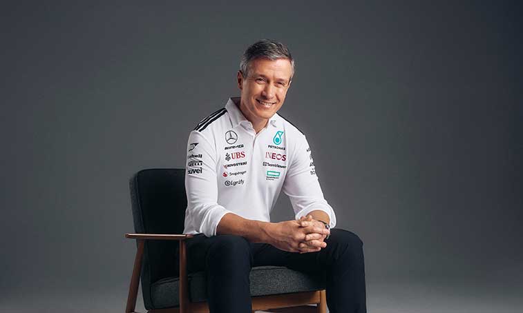 Rob Thomas wearing a Mercedes shirt smiling and sitting on a chair