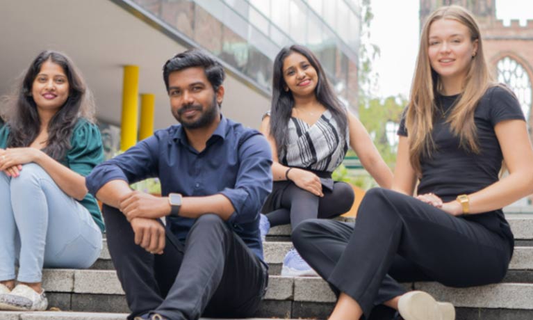 3 female students and 1 male student relaxed smiling and looking at the camera