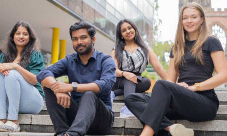 Students sitting on the steps outside of the student hub