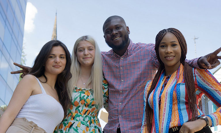 3 female students and 1 male student with their arms around them smiling looking at the camera. 