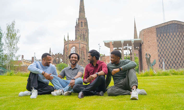 3 male students sat together and laughing looking at each other